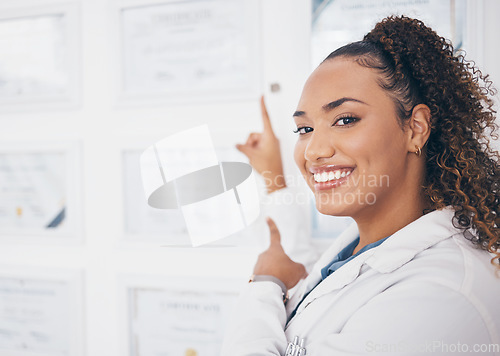 Image of Portrait, pointing and healthcare award with a woman proud of her medical achievement in the hospital. Face, smile and happy with a female medicine professional showing her certificate in a clinic