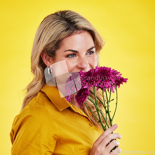 Image of Portrait, smile and woman smelling flowers in studio isolated on a yellow background. Floral, bouquet and happiness of person sniffing or female model with scent of natural plants and dahlia aroma.