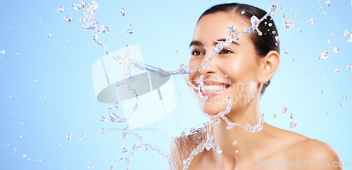 Image of Water splash, smile or happy girl with face wash for skincare or hygiene on blue background in studio. Banner, mockup or woman with wellness cleaning or washing in beauty grooming or facial treatment