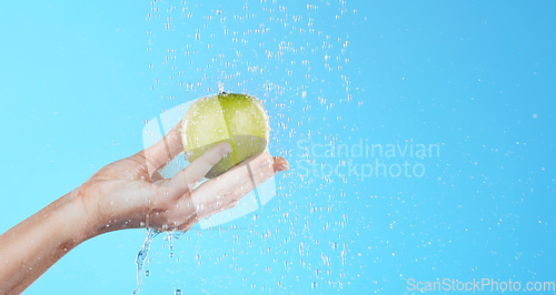 Image of Water, apple washing and hands with fruit for wellness, healthcare and nutrition self care. Healthy food, green and natural skincare with hand cleaning health snack for diet in blue background studio