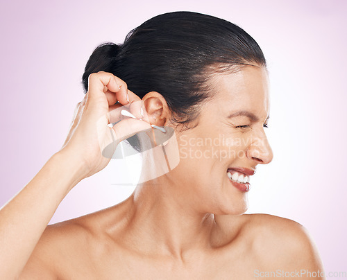 Image of Woman, cotton bud and ear in studio for cleaning, struggle or pain for wellness by pink background. Model hand, self care or clean for hygiene, ears or natural product for healthy hearing by backdrop