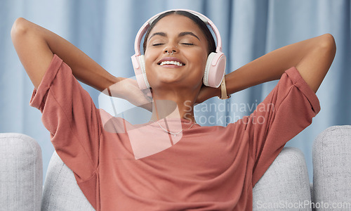 Image of Relax, headphones and woman on a living room sofa feeling peace from music. Web radio, home and podcast of a young female with a smile from zen and stress relief audio on a lounge couch in a house