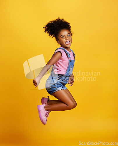 Image of Excited, jump and happy girl child jumping in happiness, joy and smile while isolated in a studio yellow background. Energy, celebrate and kid in the air due to winning, celebrating and succuss
