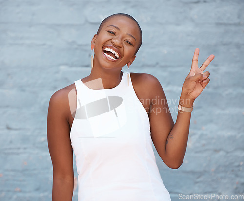Image of Portrait, hand and peace sign with a business black woman on a blue brick wall with a smile. Hand, emoji and motivation with a female employee showing a v gesture while feeling positive or confident