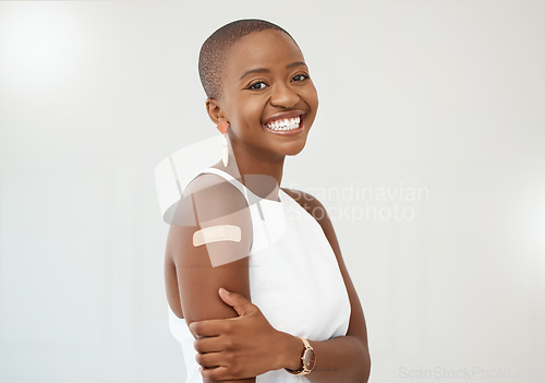 Image of Black woman, portrait and covid plaster on arm in studio for injection with medical insurance. Portrait of African female happy on a white background with healthcare vaccine, safety and mockup space