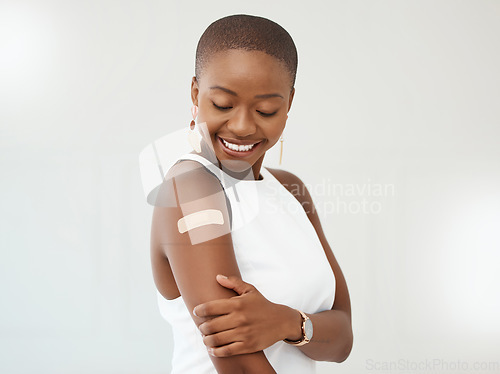 Image of Black woman, covid plaster and arm or smile in studio for injection with medical insurance. African female happy on a white background with healthcare vaccine, safety compliance and mockup space