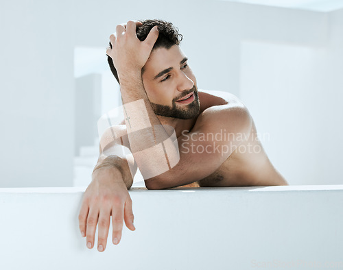 Image of Artistic, shirtless and handsome man is relaxed in a modern bathroom for hygiene and cosmetic skincare or self care. Model, male and person relax and calm in a white room for skin treatment