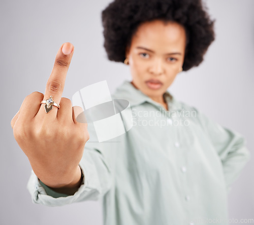 Image of Portrait of black woman, opinion and middle finger in studio, angry expression in conflict on isolated on white background. Fingers, rude hand gesture and offended, frustrated person in anger or hate