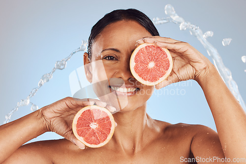 Image of Skincare, portrait and woman with a grapefruit in studio for a natural, beauty and organic face routine. Cosmetic, water splash and mature female model with a citrus fruit isolated by blue background