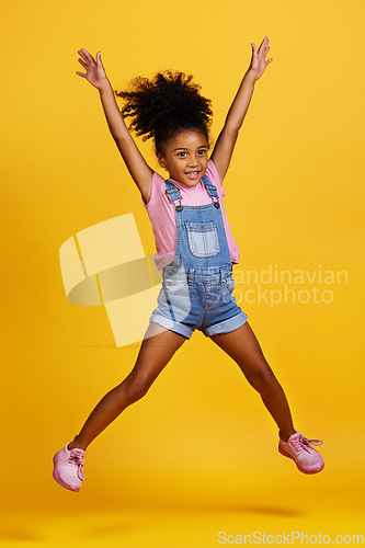 Image of Happy, jump and child hands raised jumping in happiness, joy and smile while isolated in a studio yellow background. Energy, celebrate and kid in the air due to winning, celebrating and success