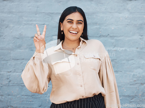 Image of Happy woman, portrait smile and peace sign in business against a gray wall background. Excited and friendly female face smiling showing peaceful hand emoji, sign or gesture with positive attitude