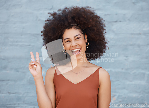 Image of Happy woman, portrait smile and afro with peace sign against a gray wall background. Excited or friendly female face smiling showing peaceful hand emoji or gesture with fun positive attitude