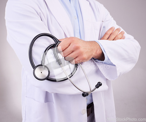 Image of Doctor, hands and stethoscope of man with arms crossed in healthcare cardiology against gray studio background. Closeup of male medical professional holding tool for checkup or heart rate monitoring