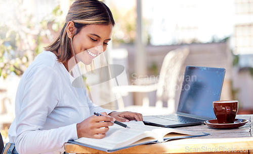 Image of Woman, reading textbook and student, education with smile and study academic course, learning and university. Happy female at outdoor cafe, book and pen for research and studying for exam with laptop