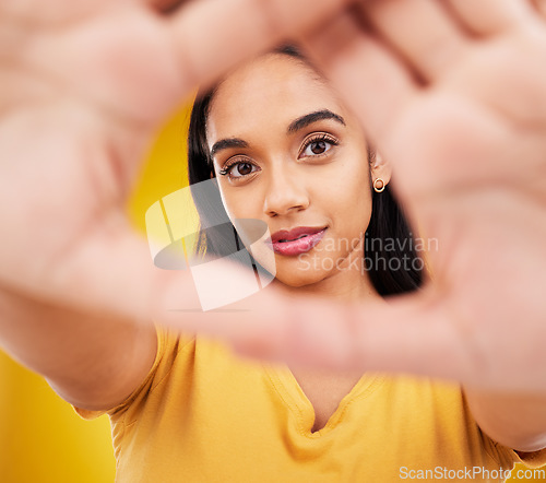 Image of Hands, frame and portrait of a woman with perspective isolated on a yellow background in a studio. Looking, creative and a girl with focus on face, shape and showing creativity on a backdrop