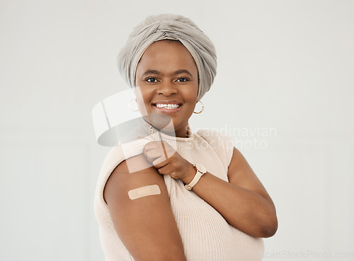 Image of Black woman, smile and covid plaster on arm in studio for injection with medical insurance. Portrait of African female happy on a white background with vaccine, safety compliance and mockup space