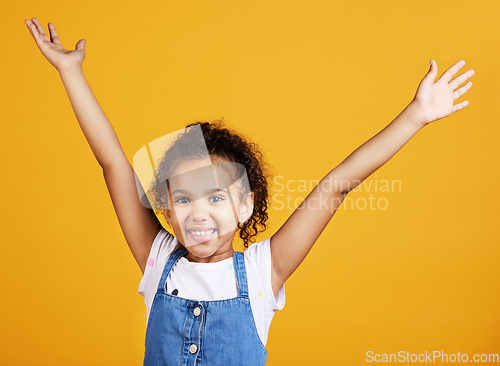 Image of Studio, portrait and excited child with hands up and smile on face on yellow background. Young girl kid with happiness, carefree and positive attitude or happy celebration or surprise announcement