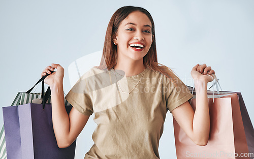 Image of Happy woman, shopping bag and portrait isolated on studio background wealth, financial freedom or sales promotion. Retail, fashion and young biracial person or gen z customer hand holding paper bags