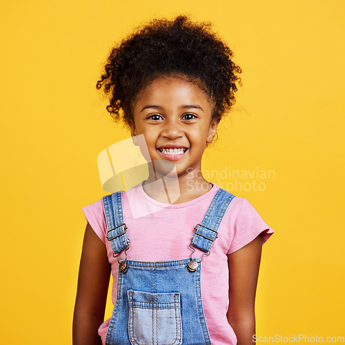 Image of Studio portrait mixed race girl looking standing alone isolated against a yellow background. Cute hispanic child posing inside. Happy and cute kid smiling and looking carefree in casual clothes