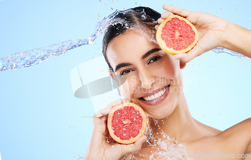 Image of Grapefruit, water or happy girl portrait with beauty in studio on blue background for healthcare or natural diet. Smile, wellness or healthy model face with fruits or vitamin c for skincare or detox