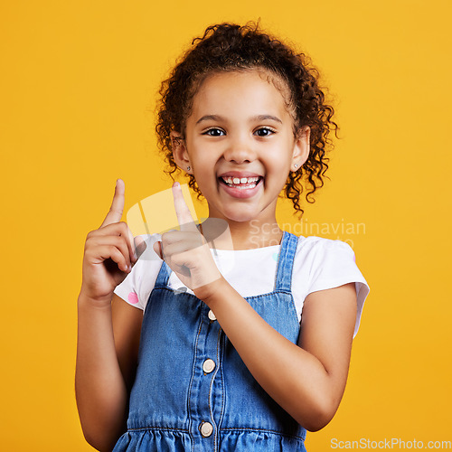 Image of Portrait, pointing up and girl with smile, branding development and happiness against a studio background. Face, female child and young person gesture for space, direction and showing with choice