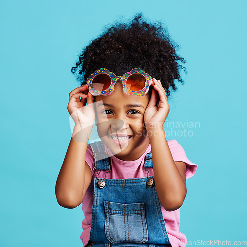 Image of Portrait, funky glasses and girl with smile, excited and cheerful against a blue studio background. Face, female child and young person with cute eyewear, trendy and happiness with joy or accessory