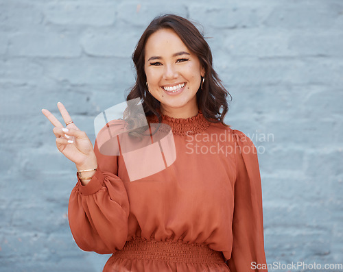 Image of Happy woman, portrait smile and beauty with peace sign against a gray wall background. Excited and friendly female face smiling showing peaceful hand emoji, symbol or gesture with positive attitude