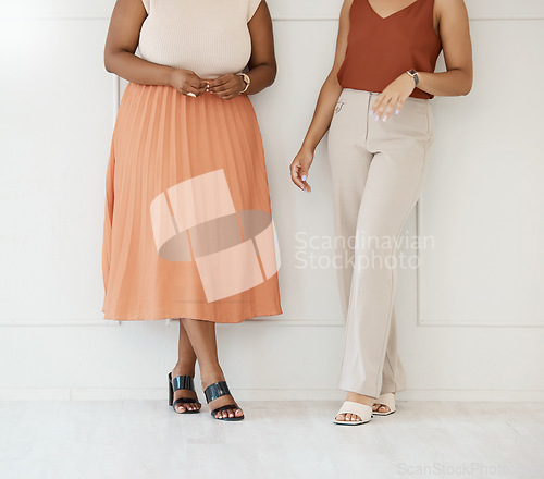 Image of Fashion, formal and business woman friends at office against a wall in team conversation or chat. Discussion, planning and legs of professional corporate employee women in luxury outfits at workplace