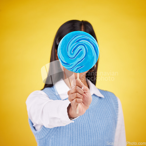 Image of cover, lollipop and candy with woman in studio for sweets, colorful snack and food. Treats, dessert and sugar confectionery with female isolated on yellow background for diet, eating and hiding