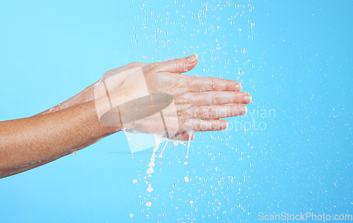 Image of Closeup woman, water drops and washing hands on blue background, studio and backdrop for sustainability. Female model cleaning hand with liquid for showering, wellness and skincare of hygiene routine