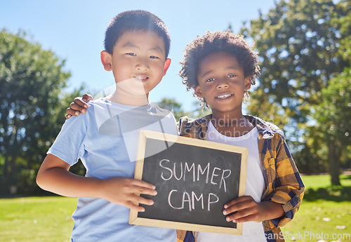 Image of Summer camp, portrait or boys hugging in park together for fun bonding, development or playing in outdoors. Happy young best friends smiling or embracing on school holidays outside with board sign