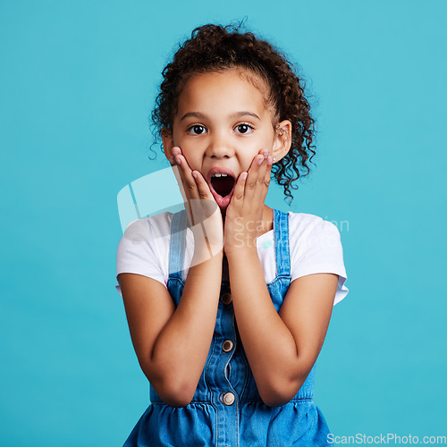 Image of Portrait, surprise and girl with wow, facial expression and happiness against a blue studio background. Face, female child and young person with shock, wow and gasp with emoji gesture and good news