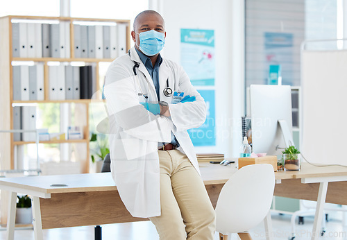 Image of Covid, portrait and a doctor black man in his office, standing arms crossed for healthcare or insurance. Medical, mask and trust with a male medicine professional at work in a wellness clinic