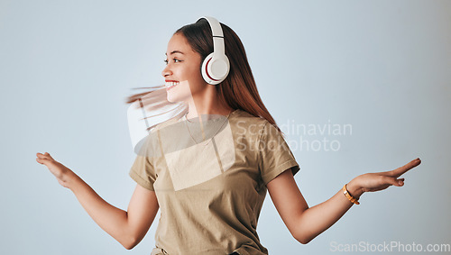 Image of Woman, music headphones and dancing in studio while happy, excited and positive. Female model on white background to dance with hands, fun and smile with energy and listening to audio or radio