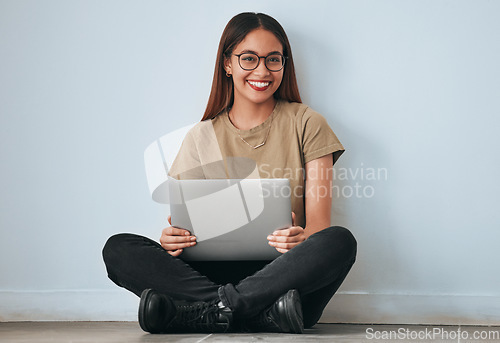 Image of Portrait, smile and student woman with laptop in home for studying, learning or education. Technology, computer and happy female sitting on floor with pc for research on wall background for mockup.