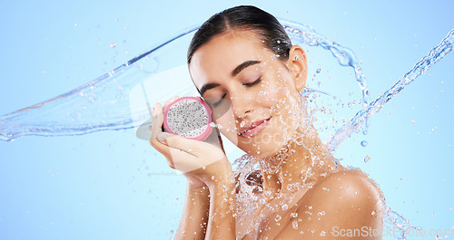 Image of Dragon fruit, water splash or woman with beauty in studio on blue background for healthcare or vegan diet. Eyes closed, skincare wellness or healthy girl model face with fruits or vitamin c to detox