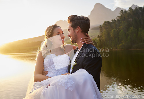 Image of Lake, wedding and man carrying his bride while having an intimate moment together in nature. Happiness, love and young couple with affection on their romantic outdoor marriage day ceremony by forest.