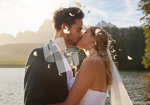 Image of Love, wedding and confetti with a couple kissing by a lake outdoor in celebration of a marriage for romance. Water, summer or kiss with a bride and groom bonding together in tradition after ceremony