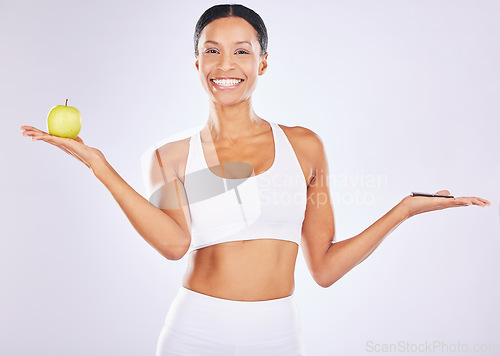 Image of Portrait, apple or happy woman with chocolate choice in studio for a healthy snack, diet nutrition or junk food. Body decision, lose weight or girl fitness model with fruits, candy or sweets options