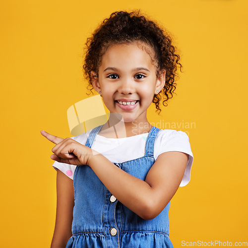 Image of Portrait, smile and girl pointing to space, direction and choice against a studio background. Face, female child and young person with gesture for decision, branding development and product placement