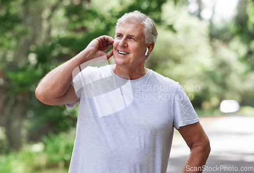 Image of Thinking, music and man with earphones while running, fitness motivation and exercise audio. Ready, smile and a senior person laughing while listening to a podcast at a park for cardio and workout