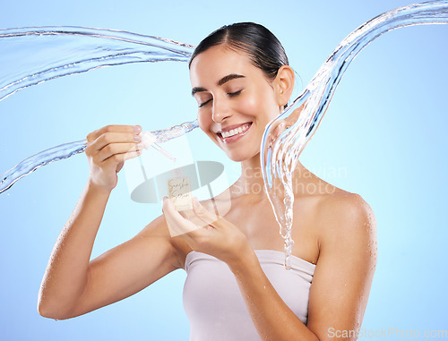 Image of Happy woman, dropper and water splash for skincare serum, product or hygiene against blue studio background. Calm female smile holding pipette for beauty cosmetics, essential oil or facial treatment