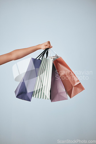 Image of Hands, shopping bags and purchase in studio sale, discount or fashion against a gray background. Hand of shopper holding bag of buying gifts, present or luxury retail products or items on copy space