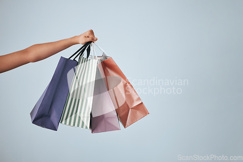 Image of Hands, shopping bags and purchase on studio mockup for fashion, discount or sale against a gray background. Hand of shopper holding bag of gifts, present or luxury retail products on copy space