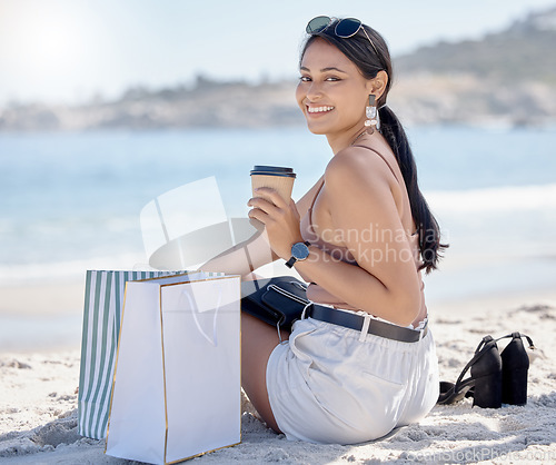 Image of Woman with shopping bag, portrait and relax on beach after retail therapy, fashion and rest with coffee. Female outdoor, latte drink and smile, happy with discount or sale with freedom and travel