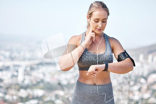 Image of Fitness, woman and smart watch checking heart rate, pulse or tracking running performance with earphones in nature. Active and fit female runner listening to music and monitoring healthy wellness