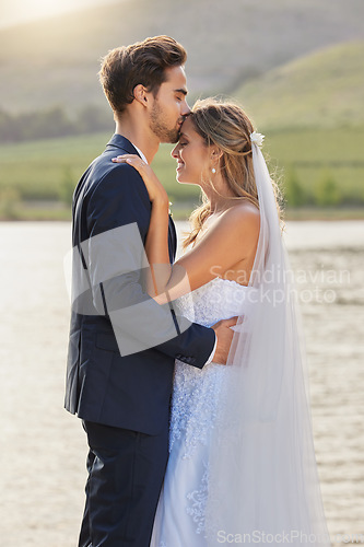 Image of Love, wedding and a couple kissing by a lake outdoor in celebration of marriage for romance as newlyweds. Water, summer or kiss with a bride and groom bonding together in tradition after ceremony