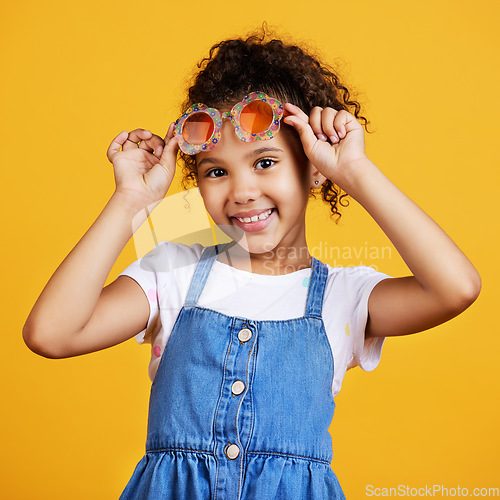 Image of Girl child, studio portrait and sunglasses with smile, happiness and summer style by yellow background. Mixed race model, female kid and fashion frame on face with kids clothes, aesthetic and youth