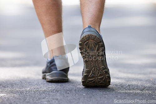 Image of Fitness, shoes and walking with a man on a street during a cardio or endurance workout outdoor. Back, exercise and health with a male runner or athlete training on a street for wellness or lifestyle