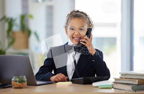 Image of Portrait, children and telephone with a business girl playing in an office as a fantasy employee at work on a laptop. Kids, phone call and a child working at a desk while using imagination to pretend